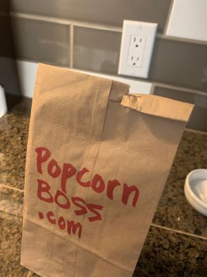 Fold the top of the paper bag about two times. Brown paper bag with popcorn kernels.