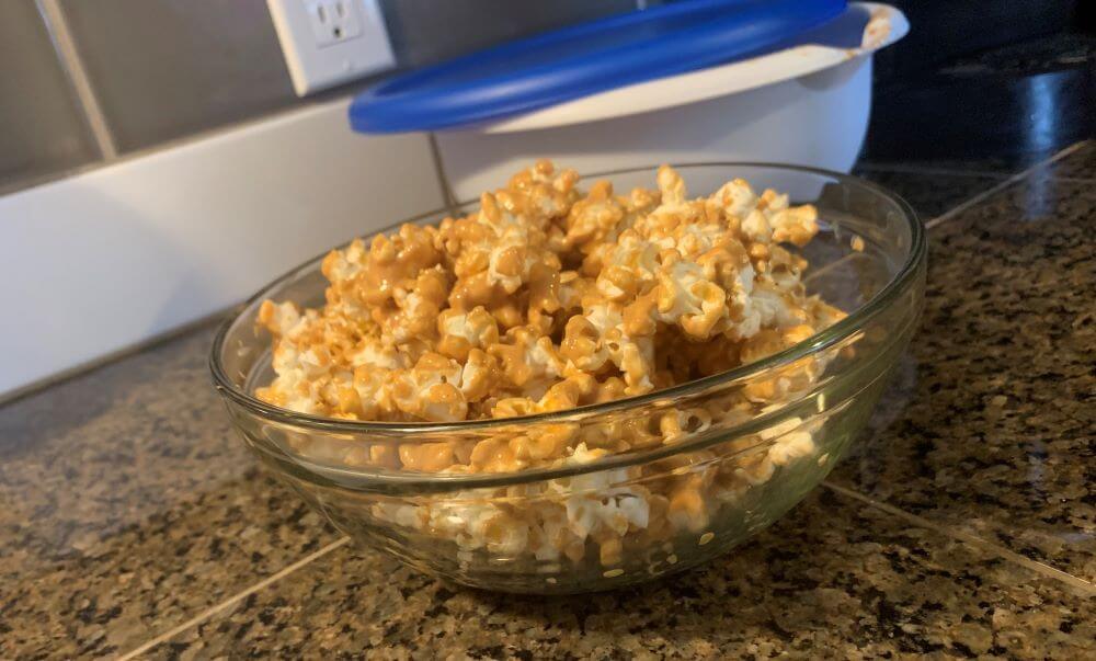 Homemade peanut butter popcorn served in a glass bowl.