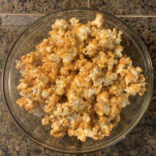 Peanut butter popcorn served in a glass bowl, and ready to be eaten.