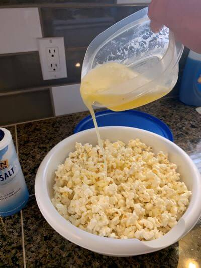 Pouring melted butter over fresh homemade popcorn. Pouring melted butter over fresh homemade popcorn.