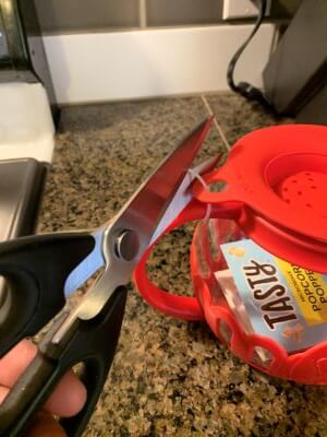 Cutting the plastic zip tie from the lid of the Tasty popcorn maker.